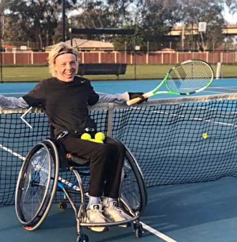 Lady in a wheelchair leaning against tennis net
