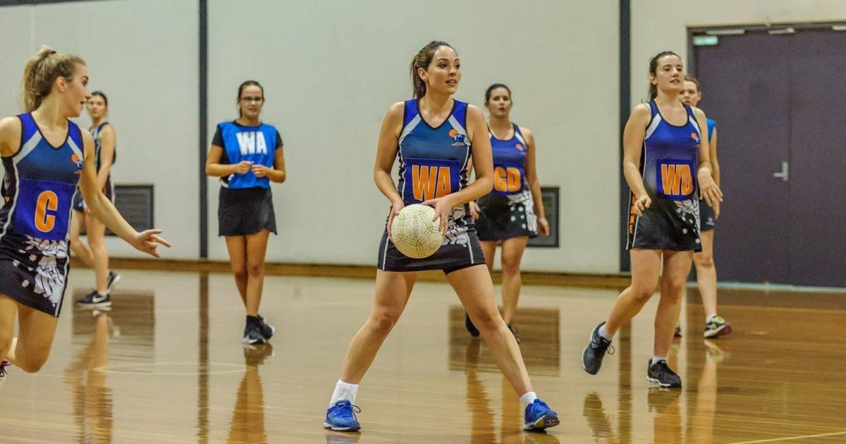 A netball team playing a game by passing the ball around.