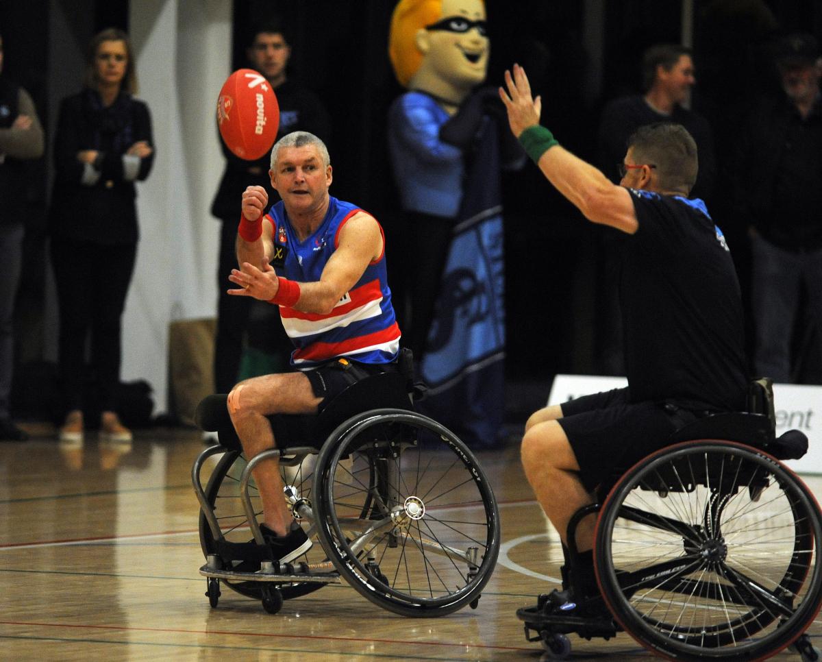 Person in wheelchair handballing football