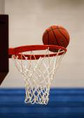 A basketball going into a white and red basketball hoop